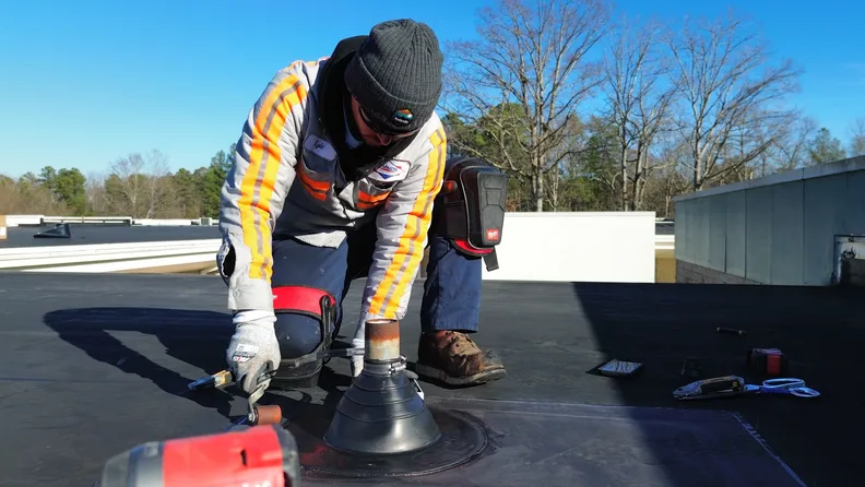 Elevated roofing team member finishing commercial flat roof